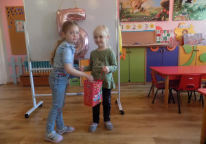 Lilianka częstuje Gabrysię urodzinowym cukierkiem.